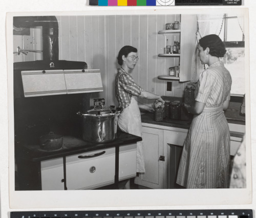 MRS. CLARENCE N. PACE CANNING ENGLISH PEAS IN HER PRESSURE COOKER, WITH LOUISE MARTIN, THE HOME MANAGEMENT SUPERVISOR, HELPING; TRANSYLVANIA PROJECT, LOUISIANA, JUNE 1940