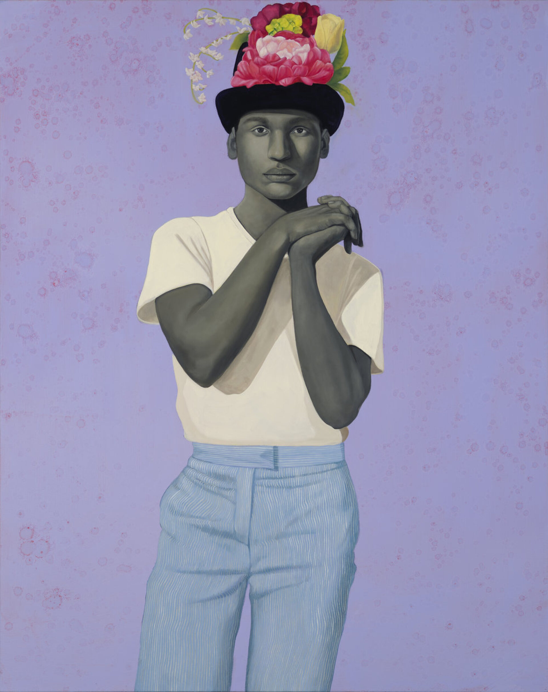 A painting depicts a person with grayscale skin, wearing a white t-shirt and light blue pinstriped pants. They stand with hands clasped, looking forward, and wear a black hat adorned with vibrant pink, yellow, and white flowers. The background is a speckled lavender.